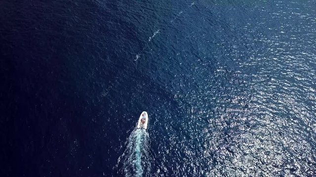 Video from above, aerial view of a rubber boat with tourists on board, sailing on a transparent and turquoise sea. Sardinia, Italy.