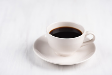 Cup of black coffee on white table