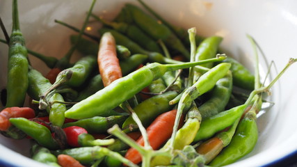 fresh red and green chilli and chopped fresh red and green chilli on wooden chopping block. guinea pepper ;bird pepper.