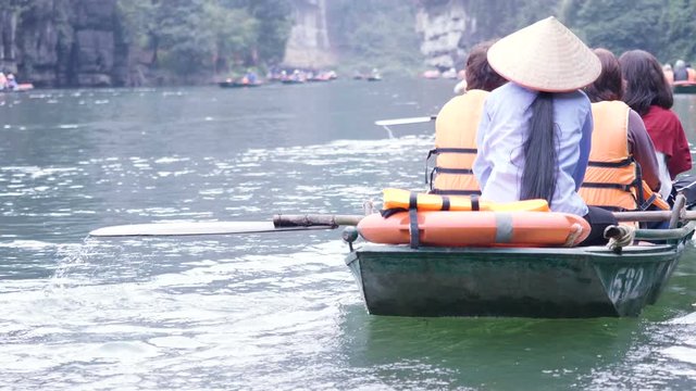 Tourist are traveling by sitting on the rowing boat in the river, Ninh Binh, Vietnam.