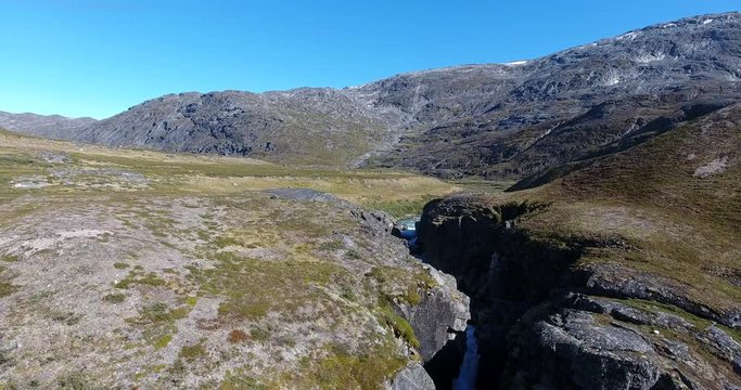 Flying over a creek to a lake in Greenland nature.