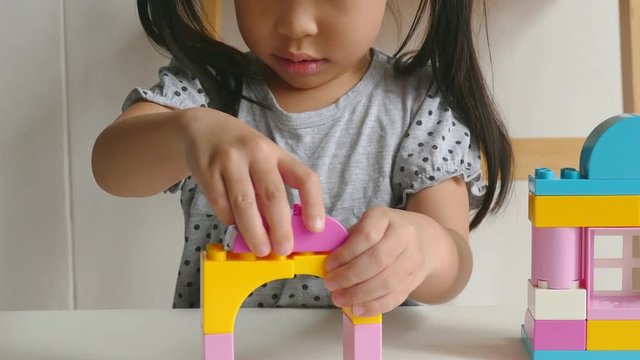 Young asian girl playing colorful plastic blocks at home