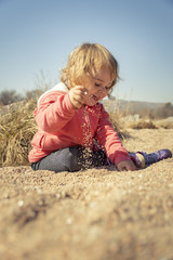 Beautiful little girl playing on the beach with sand