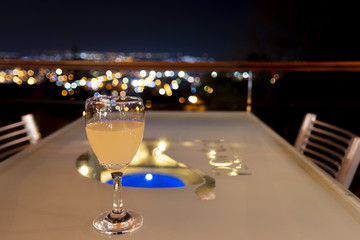 Grapefruit juice on a table with the view of Villa Carlos Paz, Cordoba, Argentina in the background, with blurred city lights