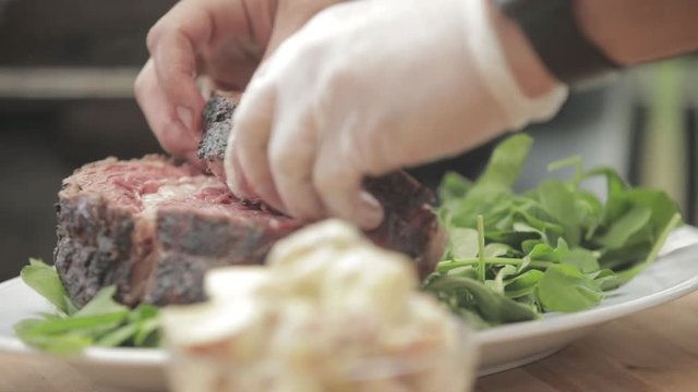 Man places prime rib on a bed of lettuce