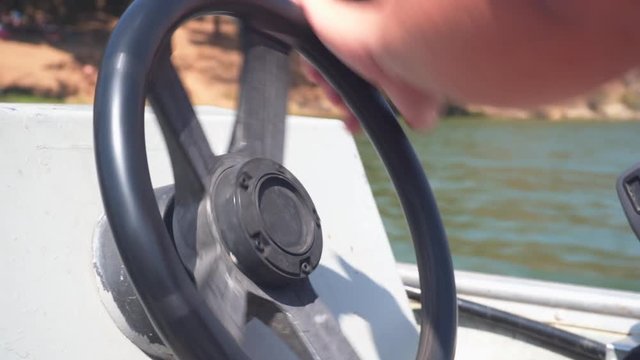 Man driving small Motorboat with Steering wheel on Californian lake with paddleboat in background