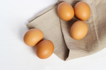 Brown chicken eggs on burlap on a white background