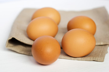 Brown chicken eggs on burlap on a white background