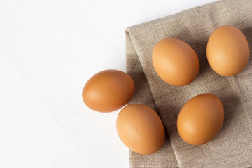 Brown chicken eggs on burlap on a white background