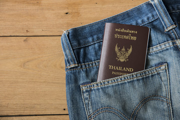 Thailand passport and blue jeans on wood