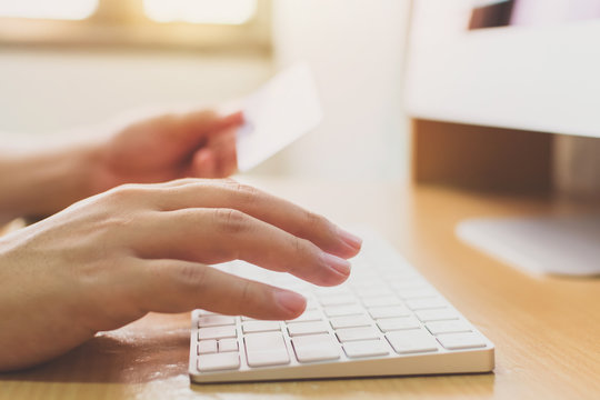 Hand holding credit card and using computer desktop. Online shopping payment and e-commerce concept