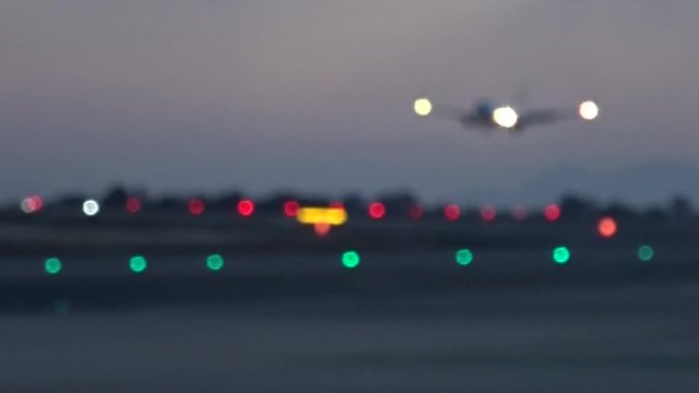 Aircraft landing on the runway full lights on. Shooted unfocused and blurry. Sunset light. May 2018. Alicante airport.
