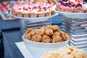 Cookies in bowl on table with many cupcake at party