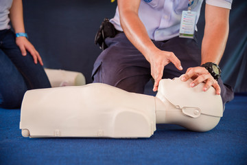 Hands of a man practicing CPR on mannequin in first aid class.