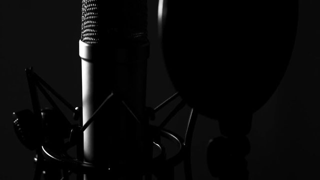 Large diaphragm condenser microphone in a music studio, lit with rembrandt lighting
(moving shot)
