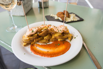 Famous Spanish dish, Patatas Bravas, or spice potatoes, served beautifully on a table with white wine in Barcelona.