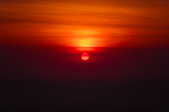 Fototapeta Sunset over ocean horizon photographed with big telephoto lens.