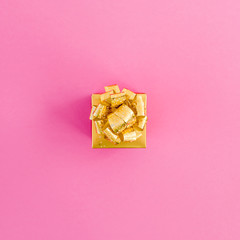 Golden gift box on pink background. New year holidays. Flat lay. Top view