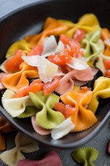 Close-up of farfalle pasta with addition of salmon and cheese, selective focus