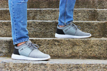 Men's legs in gray sneakers and blue jeans on the street,  step forward