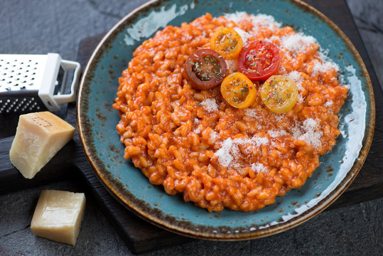 Risotto with tomatoes topped with grated parmesan and fresh sliced cherry tomatoes, studio shot