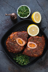 Cast-iron grill pan with uncooked marinated cross cut veal shank and gremolata, vertical shot, above view