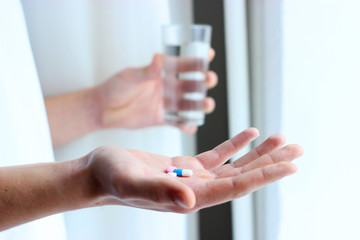 a lot of colored pills and a glass of water in the hands of men. health concept