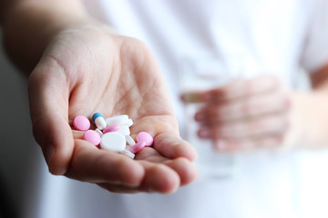  Many different colored tablets and glass of water in male hands. The concept of health. Medicine 