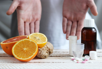 Obraz na płótnie Canvas citrus and ginger and different pills on a light background. Choose between the traditional and folk medicine. The concept of health. Male hand.