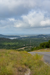 Open Road in the hill country underneath clouds and open sky.