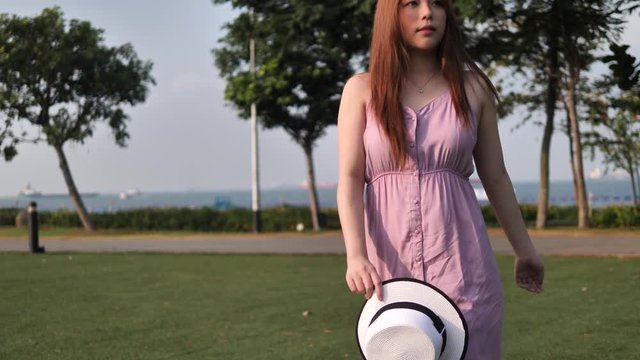 Asian chinese woman with hat walking across green lawn