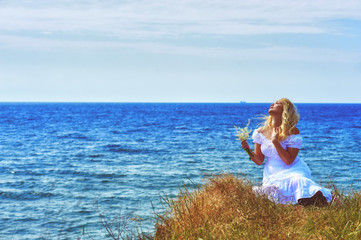 Fototapeta na wymiar Portrait of young romantic woman in white dress on sea background . Blonde girl on a walk outside the city