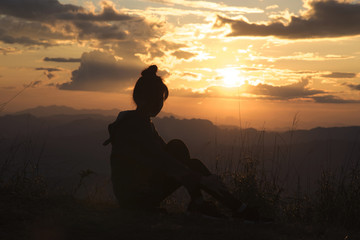 Silhouette of the Young woman looking at sunset on top mountain
