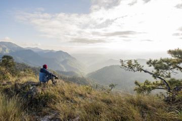 Obraz premium Man hiker sitting on a rock enjoying valley view from top of a mountain