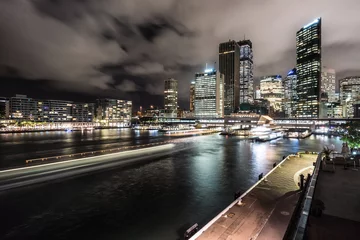 Poster Night view of the Sydney financial district skyline and the Circular Quay harbor with ferry light trails in the Sydney bay in Australia largest city © jakartatravel