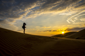 Fototapeta na wymiar gril sihouette Sand Dunes Landscape beautiful desert sunset