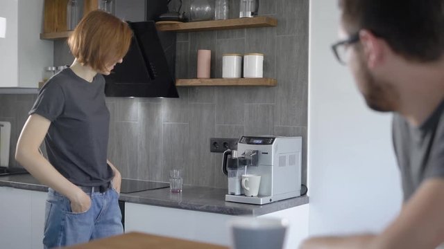 Casual woman making coffee with machine at home