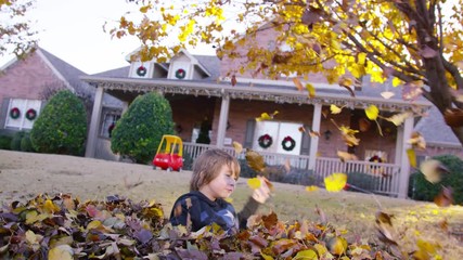 5 year old boy throws an armful of leaves into the air