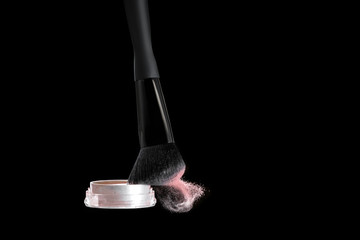 Make up brush with powder splashes on black background