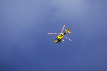 Fototapeta na wymiar Elicottero giallo di soccorso in volo su un cielo di colore blue scuro. molto drammatico