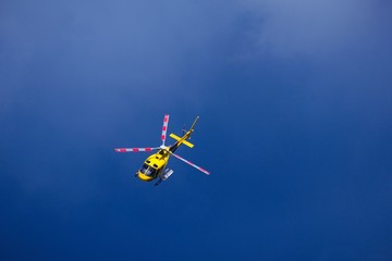 Fototapeta na wymiar Elicottero giallo di soccorso in volo su un cielo di colore blue scuro. molto drammatico