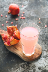 Ripe pomegranate with glass of pomegranate juice on rustic background