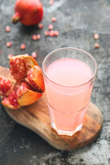 Ripe pomegranate with glass of pomegranate juice on rustic background