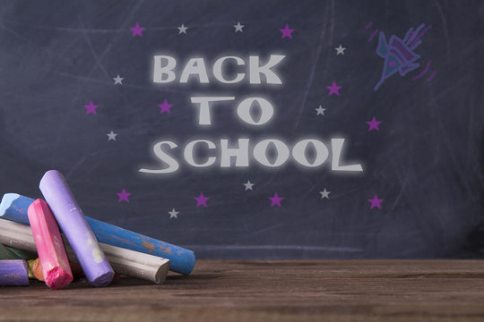 message back to school on blackboard background with rockets and stars