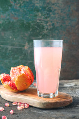 Ripe pomegranate with glass of pomegranate juice on rustic background