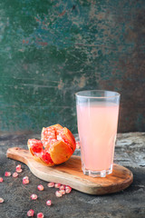 Ripe pomegranate with glass of pomegranate juice on rustic background