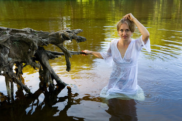Beautiful girl in a wet translucent white dress in the water.