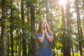 Nature, summer and people concept - Young woman posing in green forest