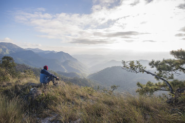 Obraz premium Man hiker sitting on a rock enjoying valley view from top of a mountain