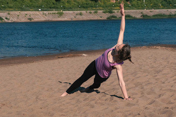 Woman doing the exercises sports on the banks of the river in the city. Exercises for hands in the plank.